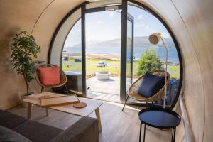 a living room with a couch and chairs and a large window at Loch Beg Pod in Pennyghael