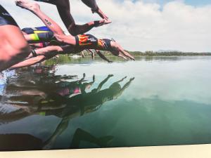 a group of people jumping into the water at Camping Bungalow el Llac de Banyoles in Porqueres