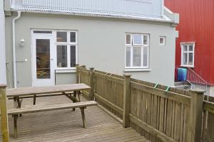 a wooden deck with a bench and a white house at Ragna's apartment downtown. in Reykjavík