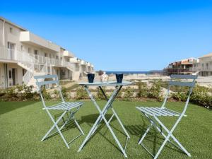 een tafel en twee stoelen op een gazon met een gebouw bij Affittimoderni - Marzamemi Luxury Residence in Marzamemi