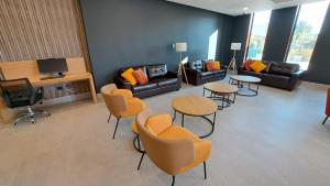 Hotel Diego de Almagro Pudahuel Aeropuerto في سانتياغو: غرفة معيشة مع كنب وطاولات وكراسي