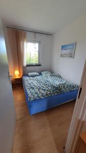 - une chambre avec un lit bleu et une fenêtre dans l'établissement Letni Zakątek, à Władysławowo
