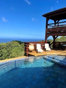 uma piscina com duas cadeiras e um gazebo em La Plantation em Saint-Joseph