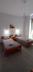 two beds in a white room with two lamps at Hermes in Kavos