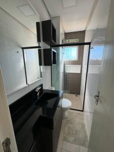 La salle de bains est pourvue d'un lavabo noir et de toilettes. dans l'établissement brisas da maré 301, à Passo de Torres