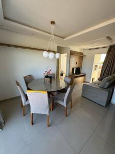 a dining room and living room with a table and chairs at brisas da maré 301 in Passo de Torres +4 photos