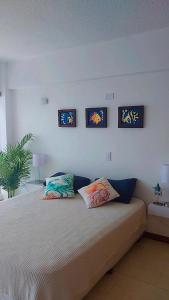 a bedroom with a bed with three pictures on the wall at Apart. con aire, frente al mar in Porlamar
