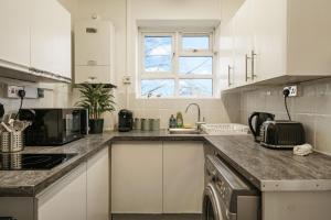 a kitchen with white cabinets and a counter top at Livestay-Two Bedroom Apartment in Clapham in London