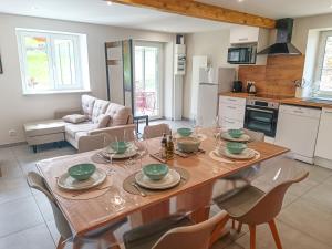 cocina y sala de estar con mesa de madera y sillas en Le gîte d'Ouillon, en Saint-Hostien