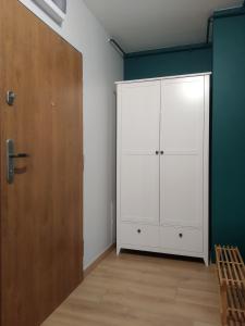 een kamer met een witte kast en een houten deur bij Apartament Białystok in Białystok
