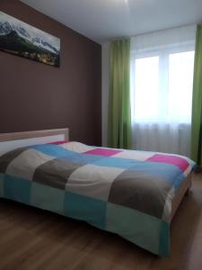 比亞韋斯托克的住宿－Apartament Białystok，卧室内一张带五颜六色棉被的床