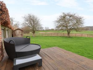 een patio met een stoel, een tafel en een veld bij The Cow Shed in Bridgnorth