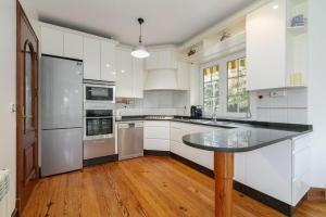 Una cocina con gabinetes blancos y una encimera negra. en La Casa De Rita, en Baiona