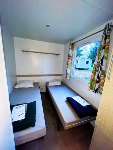 2 camas en una habitación pequeña con ventana en Charmant bungalow tout équipé avec TV - 4 personnes - proche Europapark, en Boofzheim