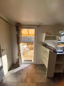 una pequeña cocina con puerta a un patio en Charmant bungalow tout équipé avec TV - 4 personnes - proche Europapark, en Boofzheim