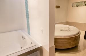 a bathroom with a round bath tub next to a toilet at Bluh Motel in Curitiba