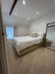ein weißes Schlafzimmer mit einem Bett und einem Spiegel in der Unterkunft Millstone Cottage Newmillerdam in Hill Top