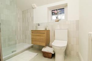 ein Bad mit einem WC, einer Badewanne und einem Fenster in der Unterkunft Millstone Cottage Newmillerdam in Hill Top
