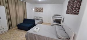 um pequeno quarto com uma cama e uma cadeira azul em Pousada dos Félix em São Gabriel