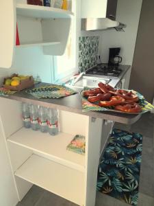 a kitchen with a table with a tray of hot dogs on it at Charmant bungalow tout équipé avec TV - 4 personnes - proche Europapark in Boofzheim