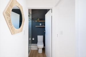 bagno con servizi igienici bianchi e specchio di The Upper Haus Cape Town Accommodation a Città del Capo