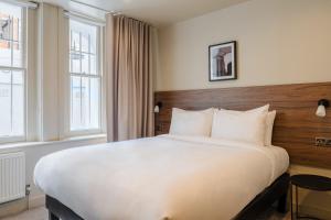 a large bed in a hotel room with windows at Sonder The Gilbert in London