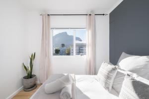 a bedroom with a white bed with a window at The Upper Haus Cape Town Accommodation in Cape Town