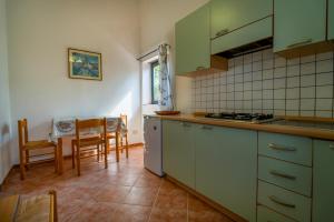 una cocina con armarios verdes, mesa y sillas en Agriturismo Il Poderino en Grosseto