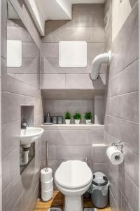 a bathroom with a white toilet and a sink at Vibrant 2-Bed by Bow in London