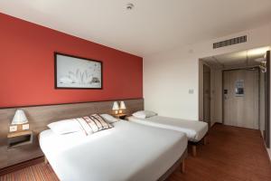 2 Betten in einem Hotelzimmer mit roten Wänden in der Unterkunft Ace Hotel Roanne in Mably + 7 Fotos