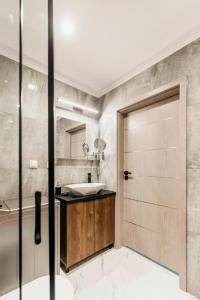 ein Bad mit einer Dusche, einem Waschbecken und einer Tür in der Unterkunft Apartament B Park City in Ostrowo