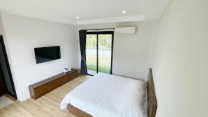 een slaapkamer met een bed en een tv aan de muur bij Spacious Private Villa Modern Style near beach in Thai Muang