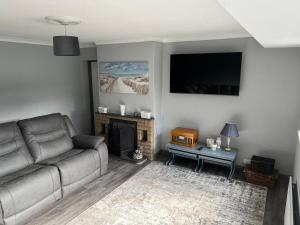 a living room with a couch and a fireplace at Dawson's Corner Retreat in Beadnell
