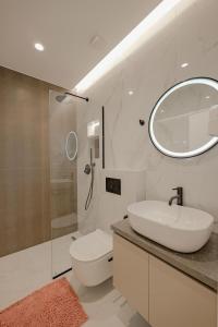 een witte badkamer met een wastafel en een spiegel bij Villa Xhefri in Sarandë