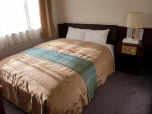 um quarto com uma cama grande e um cobertor castanho em HOTEL GATE 88 em Naruto