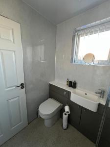a bathroom with a toilet and a sink and a window at Dawson's Corner Retreat in Beadnell +22 photos