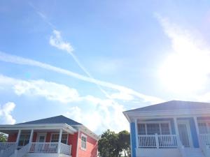 due case sedute l'una accanto all'altra sotto un cielo azzurro di Mangrove Cay Sea View Villas a Behring Point