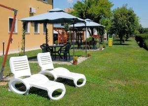 two white chairs and an umbrella in the grass at Ferienwohnung in Venedig mit Grill in Tessera
