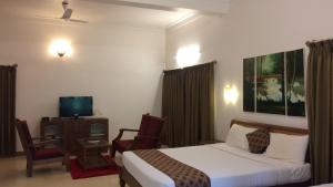 a hotel room with a bed and a chair and a television at Ibbanicadu Estate Homestay in Madikeri