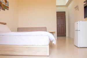 um quarto com uma cama branca e um frigorífico em Island Man B&B em Huxi