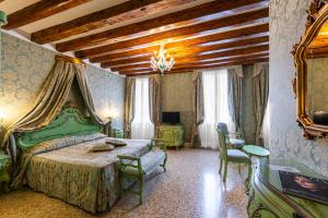 ヴェネツィアにあるホテル カドガレッサのベッドルーム(緑のベッド、テーブル、椅子付)