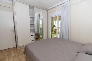 1 dormitorio con cama y ventana grande en 006 - Amplo 3 quartos com vista mar em Bombas, en Bombinhas