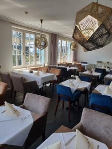 un restaurante con mesas y sillas blancas y ventanas en Hotel Seeschau en Reichenau