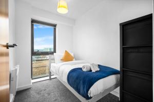 a bedroom with a bed with a blue blanket and a window at Central Flat Pool Table Balcony in Sheffield