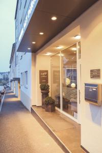 a building with glass doors and plants on a sidewalk at Hotel Restaurant Alt Pirmasens in Pirmasens