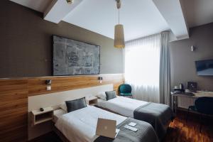 a hotel room with two beds and a desk at Hotel Beethoven in Gdańsk