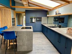 a kitchen with blue cabinets and a counter with blue stools at Luxury lodge, foot of South Downs nr beach in Ferring