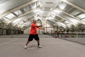 un hombre sosteniendo una raqueta de tenis en una pista de tenis en The Westin Trillium House, Blue Mountain en Blue Mountains