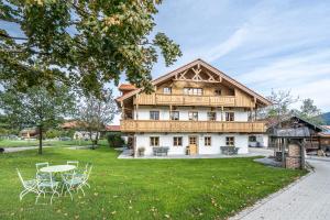 a large wooden house with a table and chairs at Pension Lenz´n am Christlhof in Lenggries