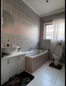 a bathroom with a tub and a sink and a toilet at DMK GUESTHOUSE 2 in Cape Town